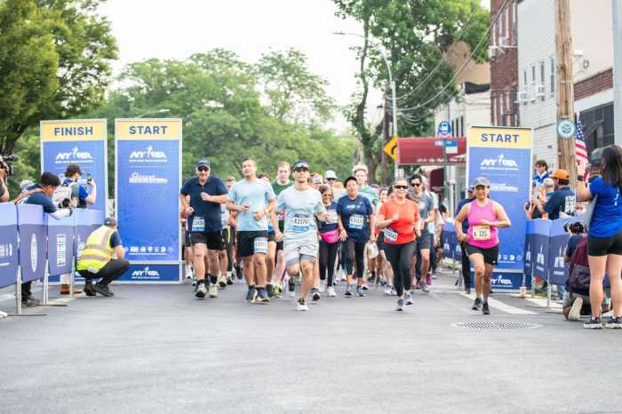A crowd of runners running past the start line at the inaugural NYRR Start Line Series run in Long Island City.