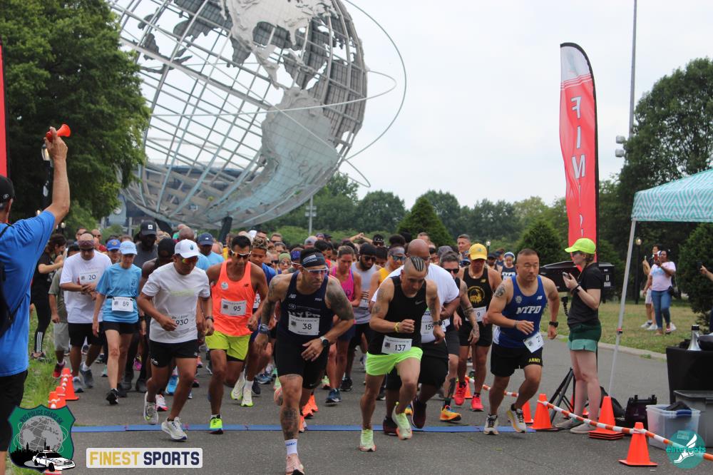 A crowd of local runners sprinting past the start line at the 2023 NYC Police Chase 5K at Flushing Meadows-Corona Park.