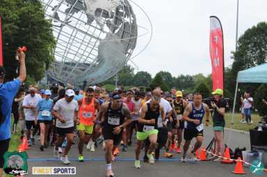 A crowd of local runners sprinting past the start line at the 2023 NYC Police Chase 5K at Flushing Meadows-Corona Park.