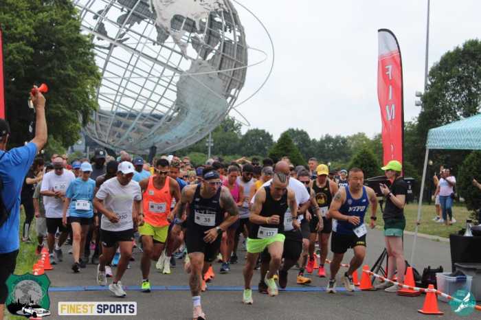 A crowd of local runners sprinting past the start line at the 2023 NYC Police Chase 5K at Flushing Meadows-Corona Park.