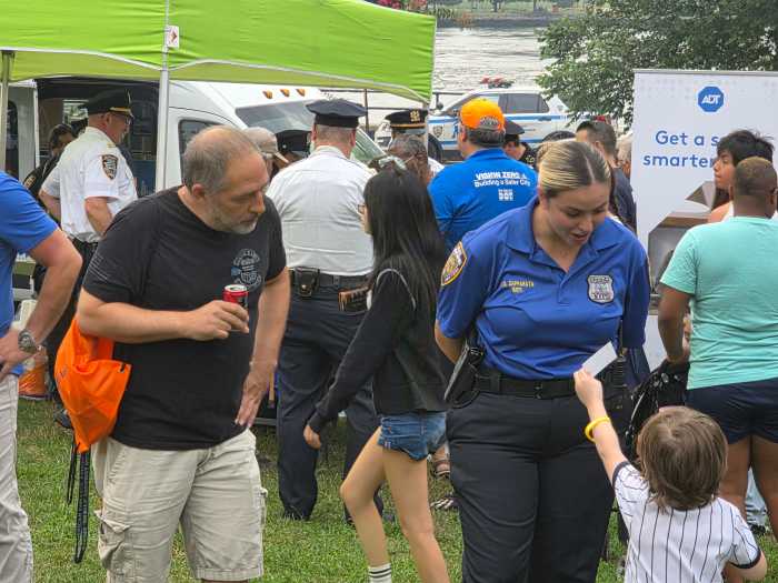 A child presents an officer from the 114th Precinct with a card at National Night Out in Astoria Park. Photo: Shane O'Brien. 