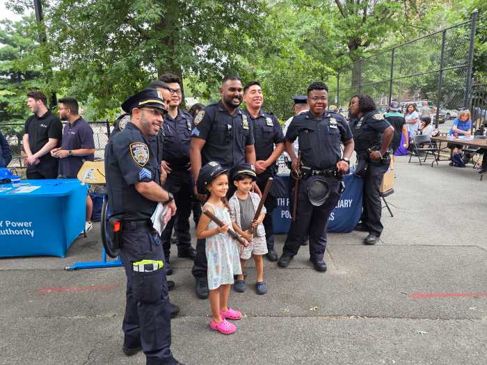 Children pose with officers from the 108th Precinct during National Night Out. Photo: Shane O'Brien.