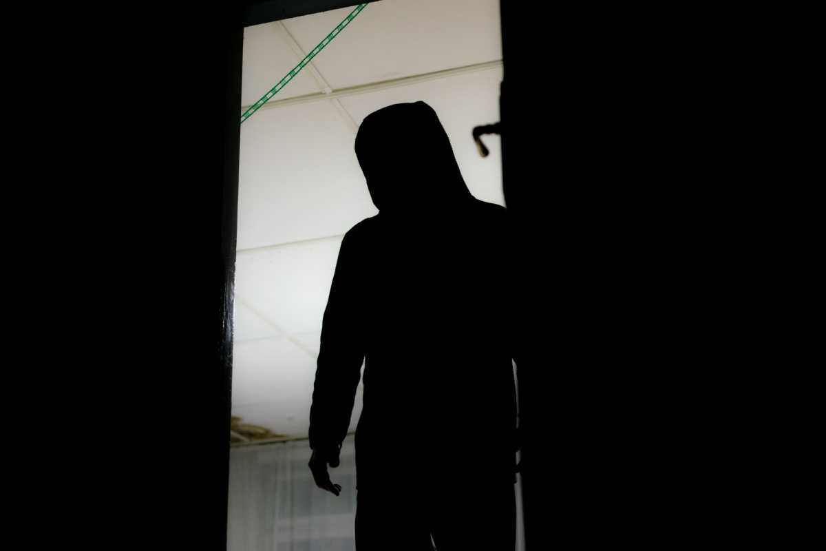 HD stock photography of a burglar entering a house, murderer stalking in the shadows and dark, with knife and a gun, killer silhouette.