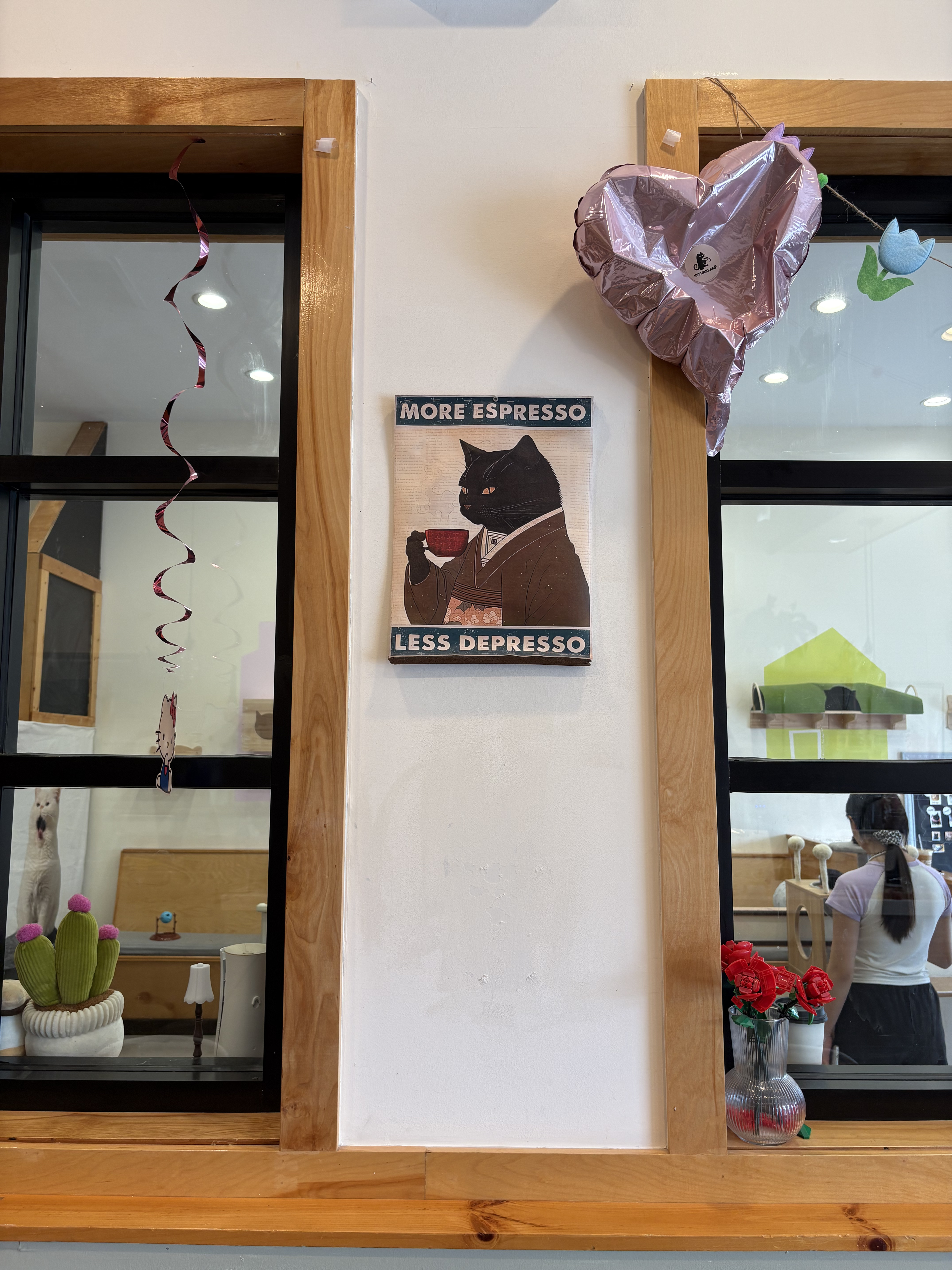 A partial view of two window panes, with a portrait that reads "More Espresso, Less Depresso," at Espurresso Cat Cafe in Bayside.