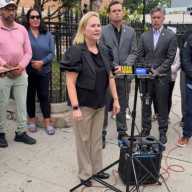 Parent Gabriella Labouriau speaks at a protest outside St. Demetrios against planned bike lanes along 31st Street. Photo 31st Street Business Assocation.
