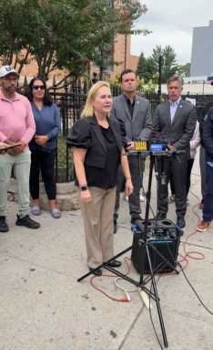 Parent Gabriella Labouriau speaks at a protest outside St. Demetrios against planned bike lanes along 31st Street. Photo 31st Street Business Assocation.