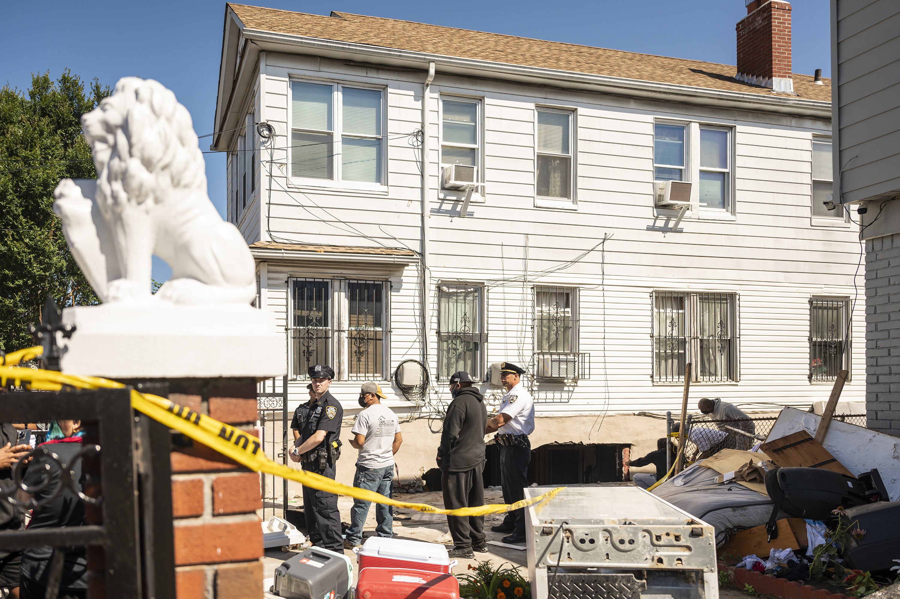 NYPD officers stand at the driveway of a Hollis, Queens, homes where two people died during Wednesday night’s flooding, Sept. 2, 2021.