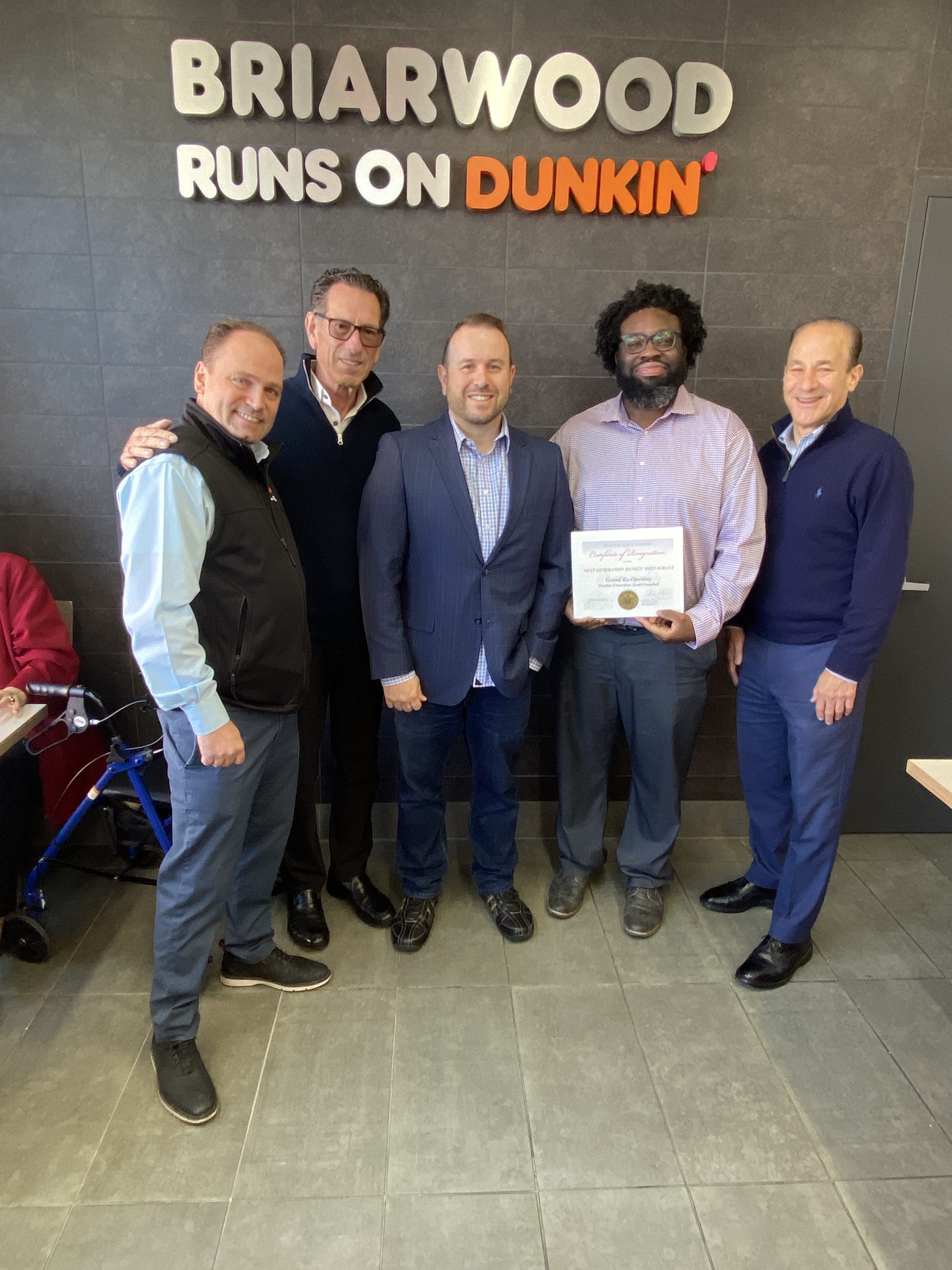 Community Liaison Anthony Harrison presented a special proclamation to representatives from Metro Franchising on behalf of the Office of state Sen. Leroy Comrie during the Briarwood Dunkin’ grand reopening.