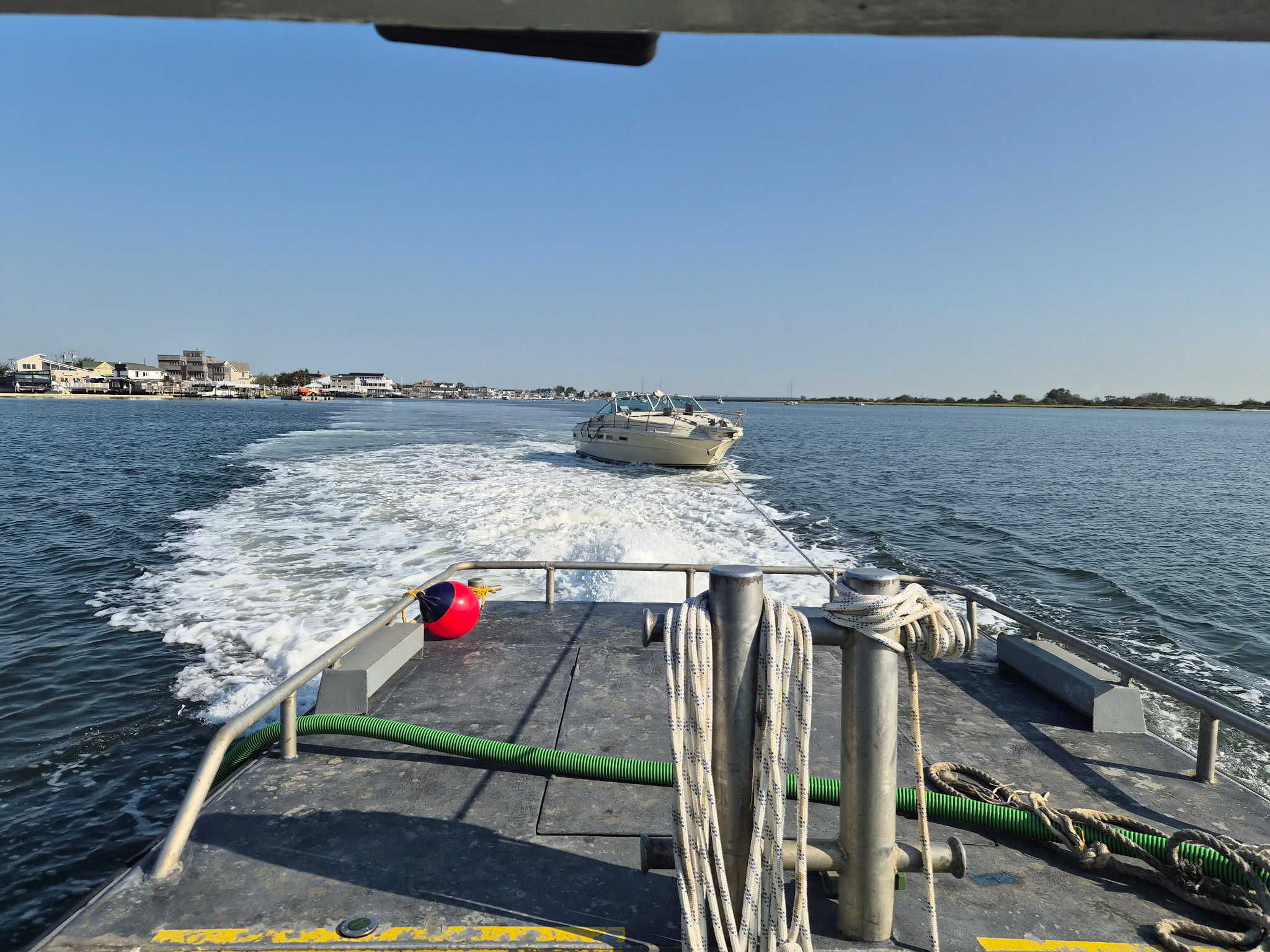A 34' Sea Ray under tow from Broad Channel.