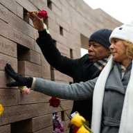 Adams places a flower on a wall dedicated to victims of Flight 587 in Belle Harbor. Photo courtesy of Mayoral Photography Office/Michael Appleton.