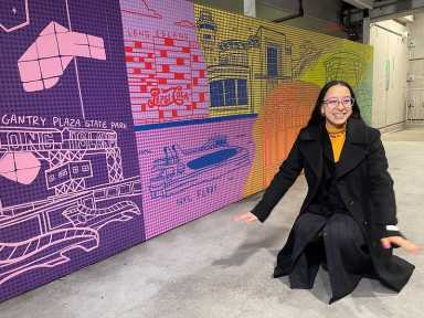 Astoria artist Brittney Rios, AKA Plushie, poses alongside her newly-installed mural in the parking garage at LaGuardia Airport's Terminal B. Photo via Port Authority Flickr.