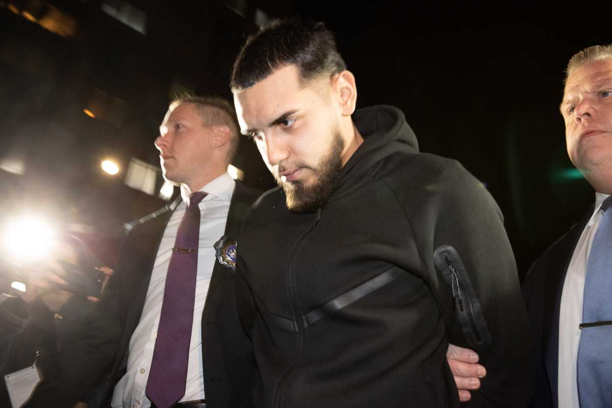 Justin Aguilera is led out of the 109 Precinct on Dec. 4, 2025, following his arrest on gang assault, assault, riot and trespassing charges.