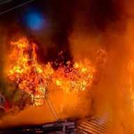 Firefighters battled a two-alarm fire at 70-07 57th Road after the blaze spread to a neighboring home.