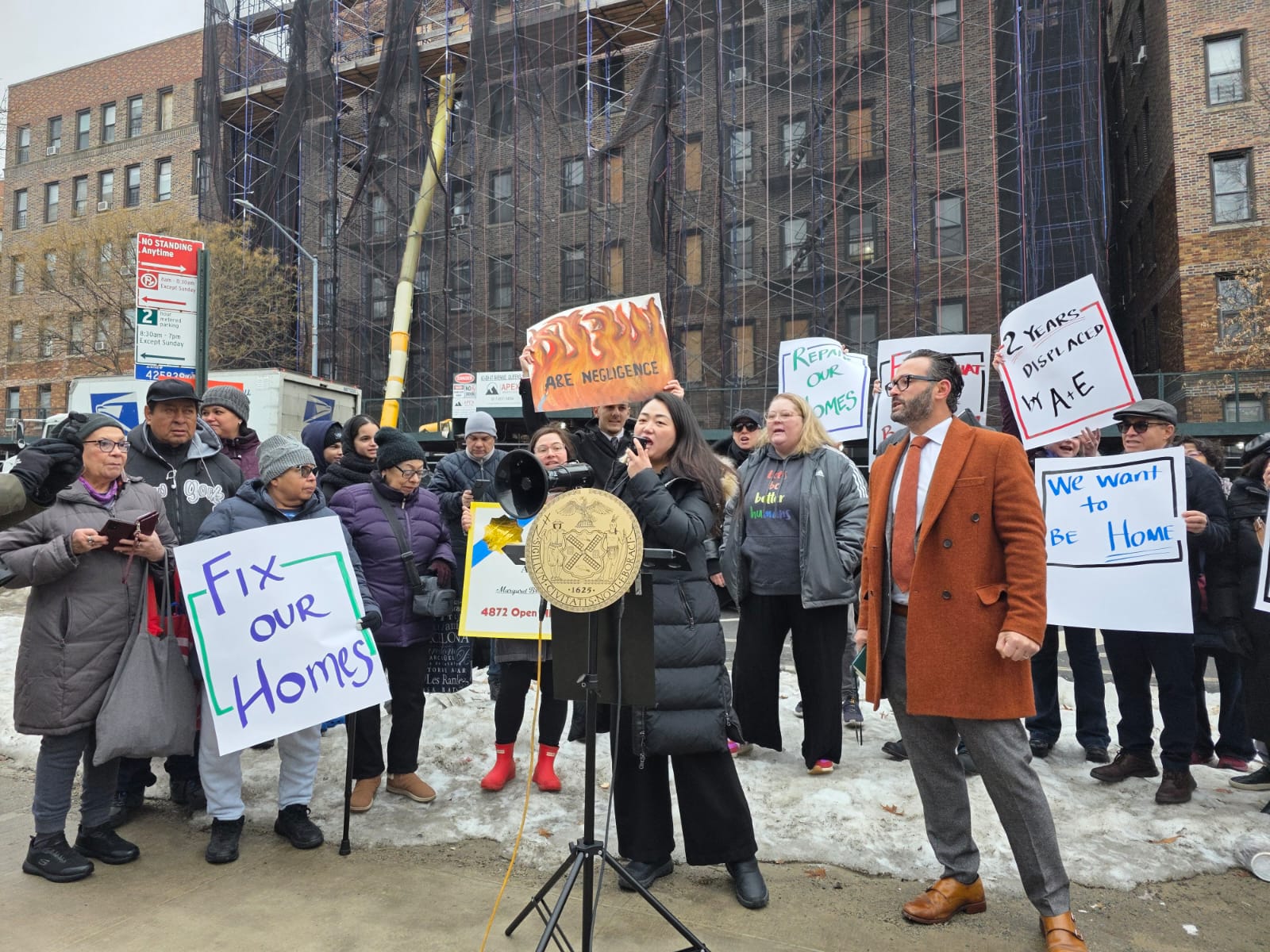 Council Member Julie Won and displaced tenants rally outside a Sunnyside building destroyed by fire.